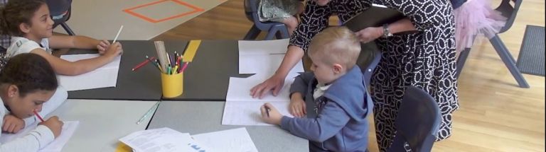 Educator helping child with task at table