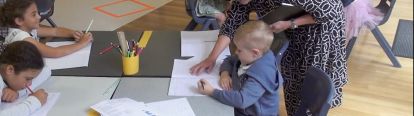 Educator helping child with task at table