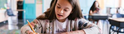 Young female student writing in notebook in a classroom